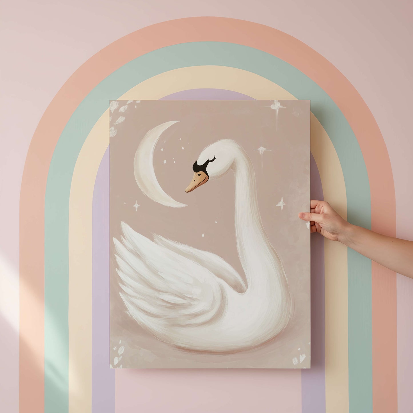 Hand holding a painting of a swan against a pastel rainbow arch.