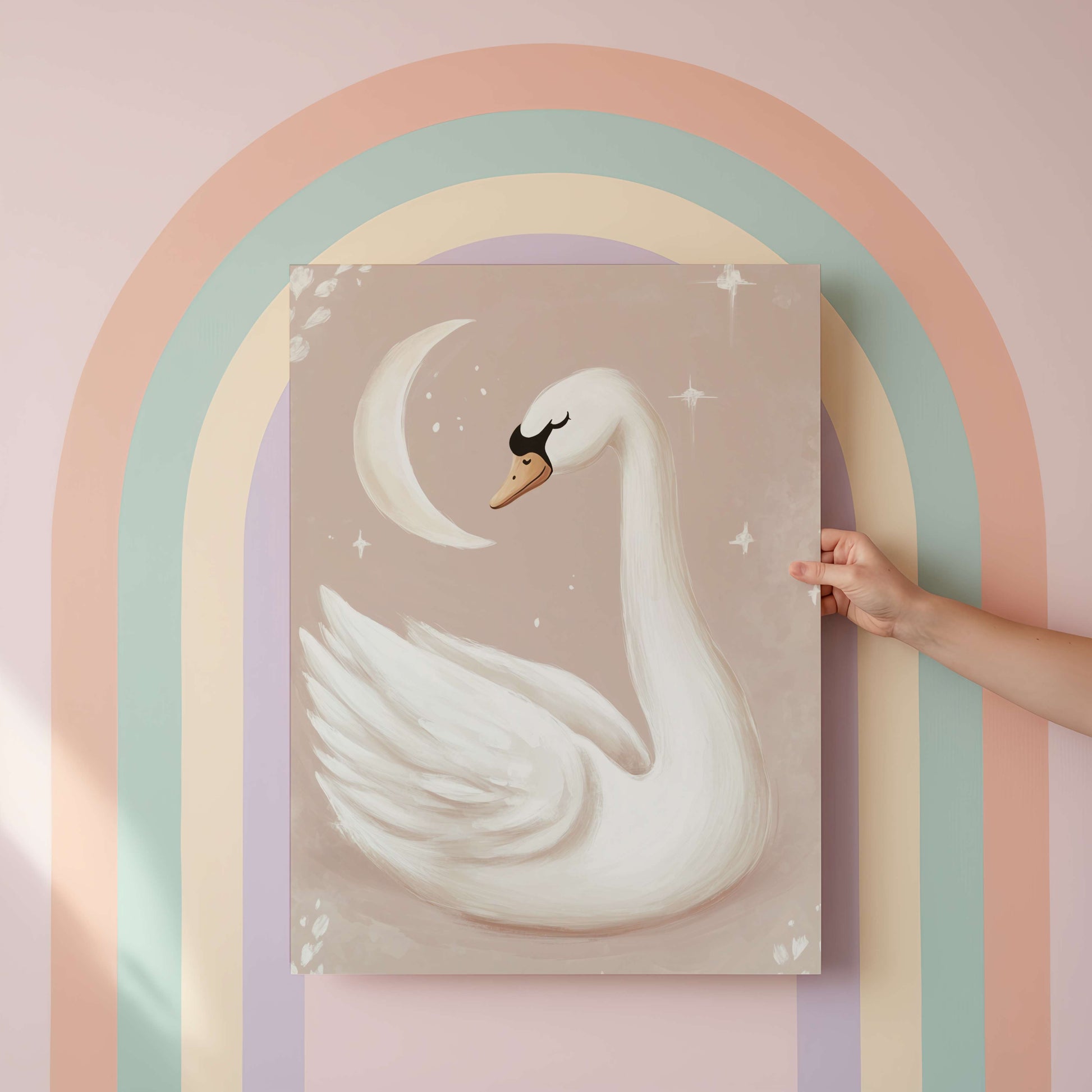 Hand holding a painting of a swan against a pastel rainbow arch.