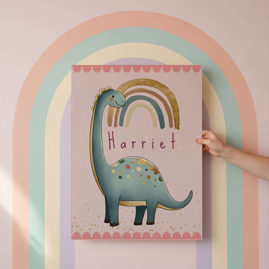 Children's poster with a dinosaur and rainbow design, held by a hand against a pastel rainbow arch.