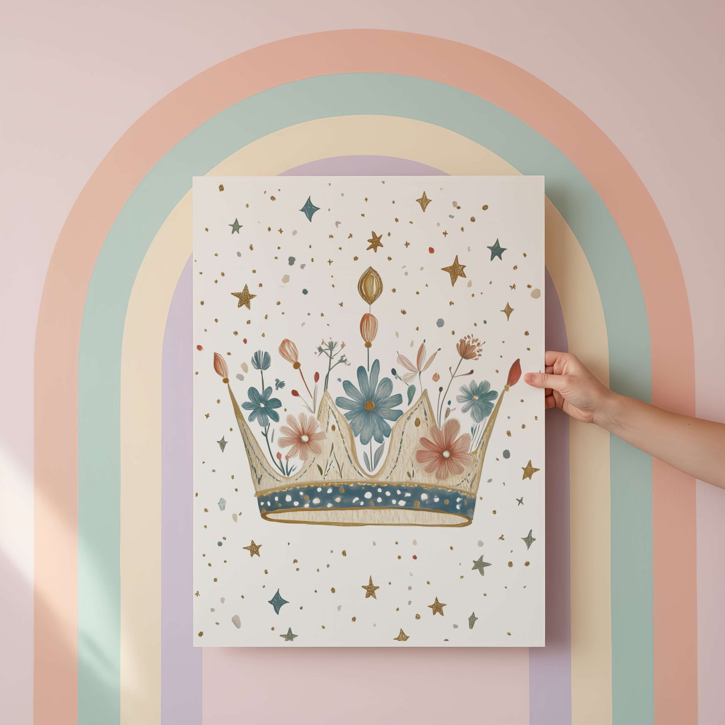 Hand holding a poster with a floral crown design against a pastel rainbow arch.