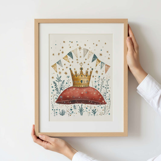 Framed artwork with a crown and decorative elements held by a person against a white wall.