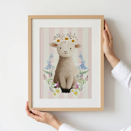 Framed artwork of a lamb with flowers held by a person against a white background